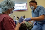 U.S. Air Force Maj. Hillary Homburg (left) and Airman Basic Kalysta Keaton, an orthodontist and dental technician, respectively, assigned to the 130th Medical Group, work on a patient during their Medical Facility Annual Training (MFAT) on July 20, 2023, at Sigonella Naval Air Station, Italy. MFAT allows National Guard medical personnel to receive real-world experience in a military medical facility. (U.S. Air National Guard photo by 2d Lt. De-Juan Haley)