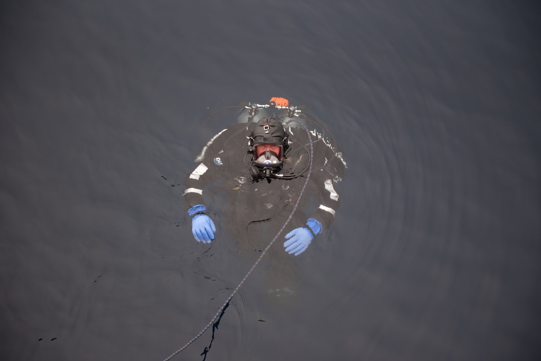 A diver looks up at the camera from the water.