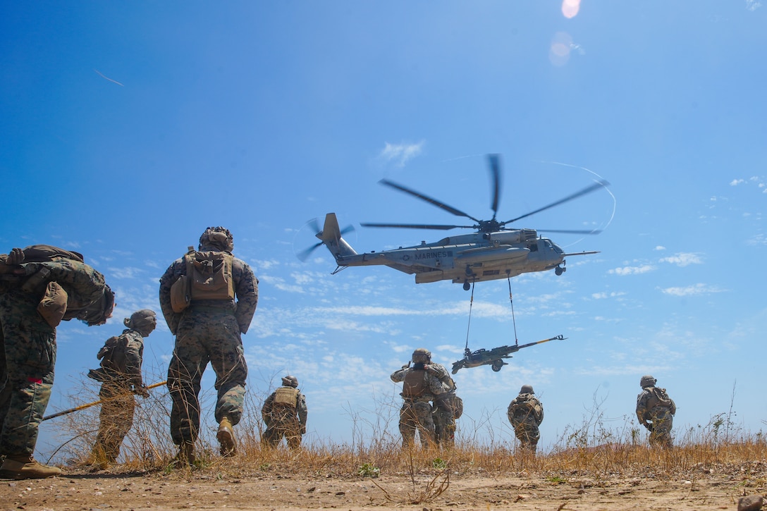 U.S. Marines assigned to Combat Logistics Battalion 15, 15th Marine Expeditionary Unit, observe as a CH-53E Super Stallion attached to Marine Medium tiltrotor Squadron (VMM) 165 (Reinforced), 15th MEU, lifts an M777 towed 155mm howitzer during a helicopter support team training at Marine Corps Base Camp Pendleton, California, Aug. 3, 2023. HSTs are responsible for the rapid transportation of cargo via helicopter for ship-to-shore movements, or movement to expeditionary sites when ground transportation is not feasible. (U.S. Marine Corps photo by Lance Cpl.  Kahle)