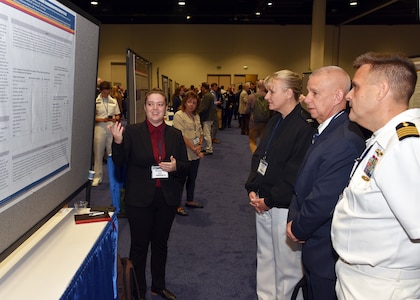 KISSIMMEE, Fla. – (Aug. 15, 2023) – Meaghan Rose, a research scientist assigned to Craniofacial Health and Restorative Medicine Directorate, Naval Medical Research Unit (NAMRU) San Antonio, briefs her research titled “Evaluation of Teledentistry Cases in Active Duty Personnel on the Global Teleconsultation Portal from 2015 to 2020” to NAMRU San Antonio leadership during a poster session held on day two of the 2023 Military Health System Research Symposium (MHSRS) held at the Gaylord Palms Resort and Convention Center. The MHSRS brings together military, government, academia, and industry experts for four days of critical conversations and intensive idea sharing. Presenters will share their latest research findings and challenges on topics including combat casualty care, military operational medicine, clinical and rehabilitative medicine, medical simulation and information sciences, military infectious diseases, and the radiation health effects. NAMRU San Antonio is one of the leading research and development laboratories for the U.S. Navy under the Department of Defense (DoD) and is one of eight subordinate research commands in the global network of laboratories operating under the Naval Medical Research Command in Silver Spring, Md.  Its mission is to conduct gap driven combat casualty care, craniofacial, and directed energy research to improve survival, operational readiness, and safety of DoD personnel engaged in routine and expeditionary operations. (U.S. Navy photo by Burrell Parmer, NAMRU San Antonio Public Affairs/Released)