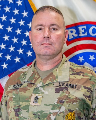 Male Soldier posed in front of the U.S. flag and U.S. Army Recruiting Flag.