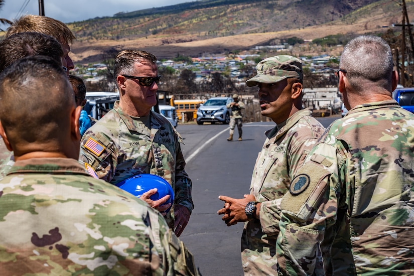 Uniformed soldiers talk in a parking lot.