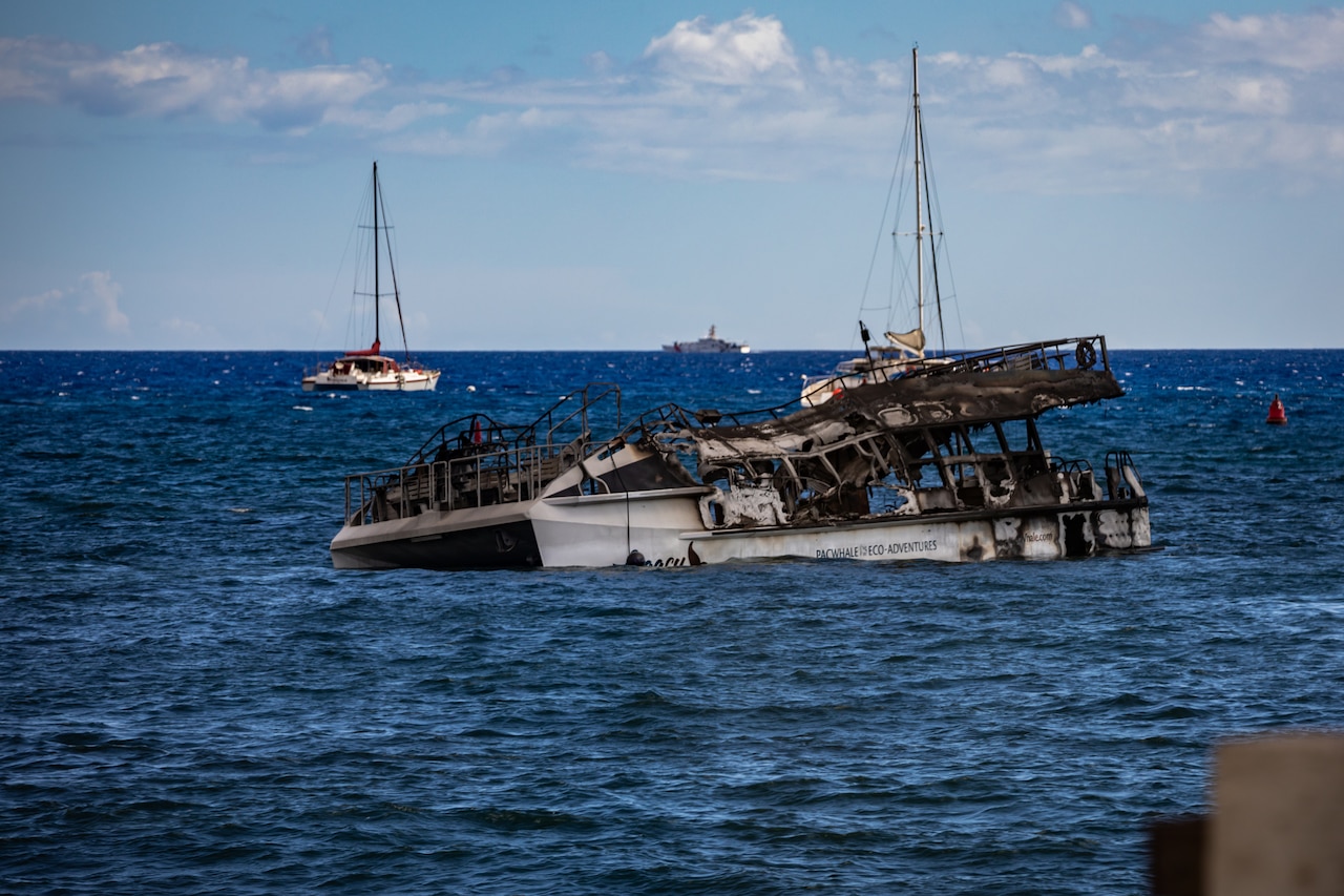 A wildfire-damaged catamaran is pictured in blue ocean water.