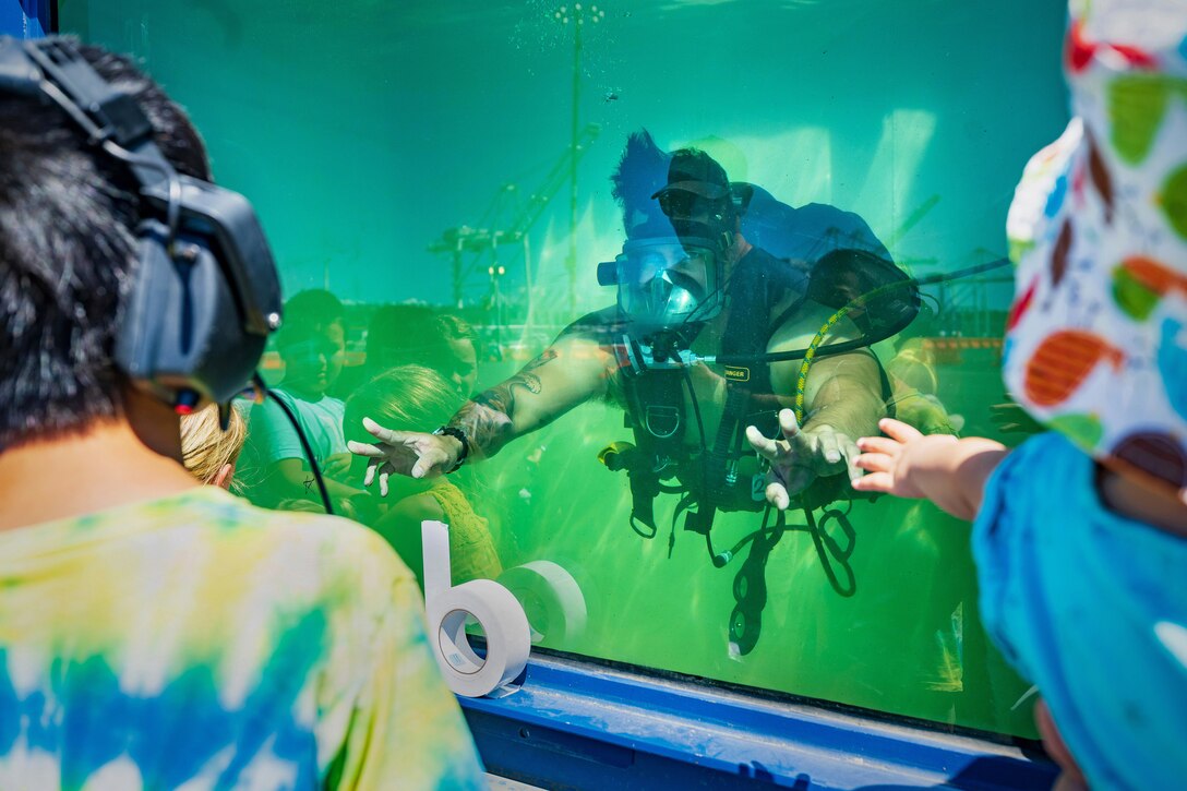 Navy Diver Petty Officer First Class Jeremy Melson, Everett Dive Locker, interacts with visitors Aug. 3, 2023, during the annual SeaFair celebration on Pier 46 in Seattle. Visitors were able to communicate with divers using a headset. (U.S. Navy photos by Wendy Hallmark)