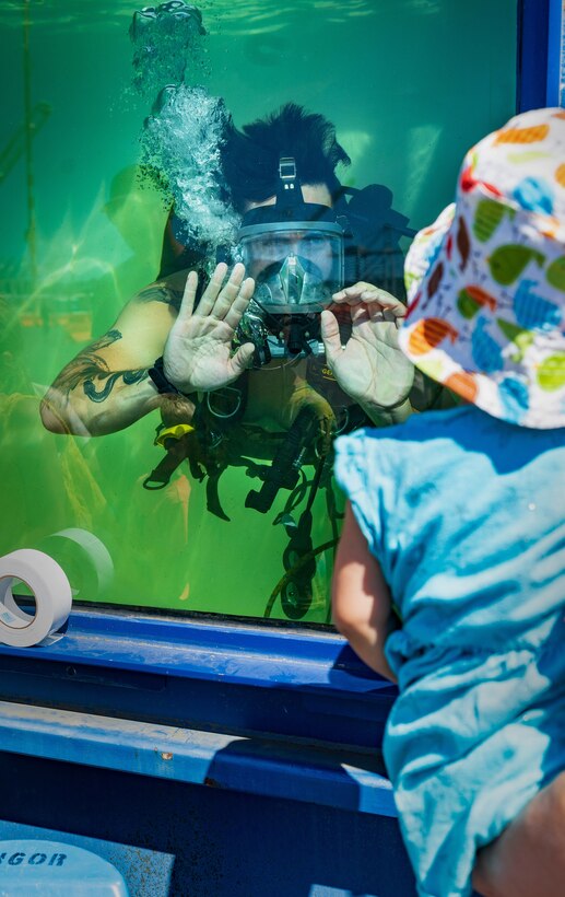 Navy Diver Petty Officer 1st Class Jeremy Melson, Everett Dive Locker, waves to a young Seafair attendee on Pier 46 in Seattle, Aug. 3, 2023, during Seafair. (U.S Navy Photo by Wendy Hallmark)
