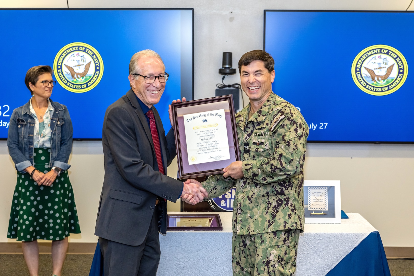 Capt. JD Crinklaw, commander, Puget Sound Naval Shipyard & Intermediate Maintenance Facility, presents Richard Tift, outgoing executive director of PSNS & IMF, with his official Certificate of Retirement July 27, 2023.