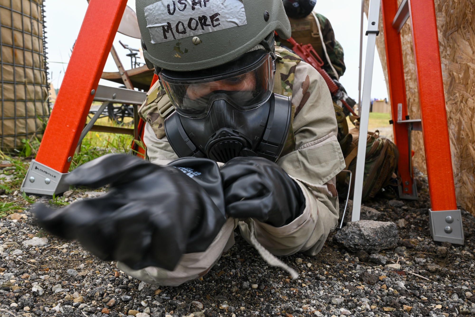 Staff Sgt. Aimee Moore, a medical technician assigned to the 433rd Medical Squadron at Joint Base San Antonio-Lackland, Texas, takes cover and adjusts MOPP gear during a simulated chemical attack as part of Exercise Patriot Medic at Youngstown Air Reserve Station, Ohio, Aug. 16, 2023.