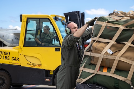 Soldiers and Marines transport cargo onto a military aircraft.
