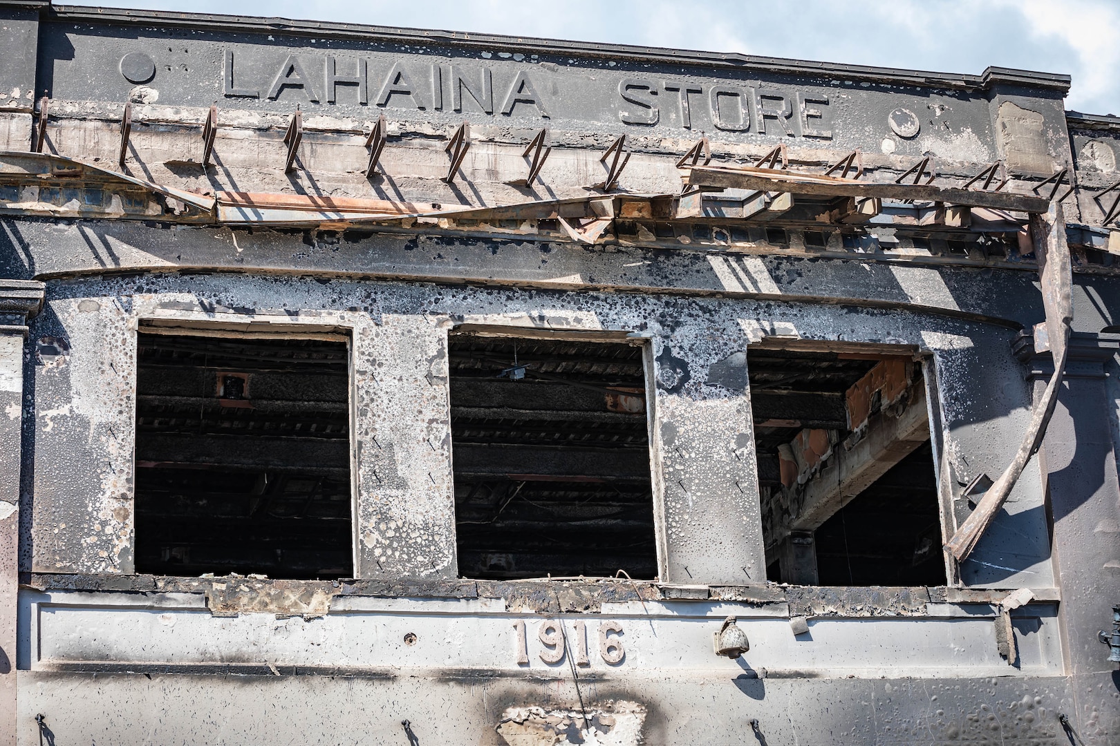 A wildfire-damaged building is shown during daylight.