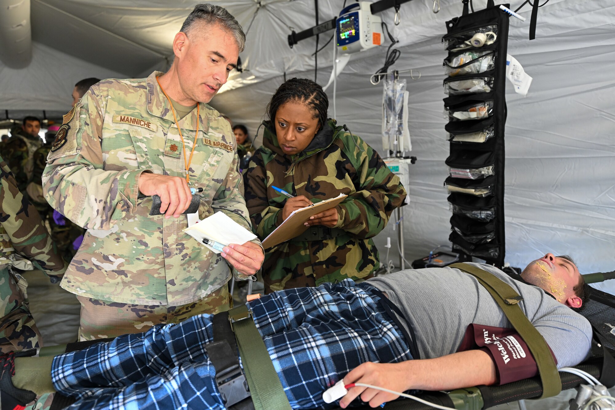 Maj. Robert Manniche, a member of the 349th Medical Squadron, Travis Air Force Base, California, provides patient information to a Reserve Citizen Airman medic during a simulated chemical attack as part of Exercise Patriot Medic at Youngstown Air Reserve Station, Ohio, Aug. 16, 2023.