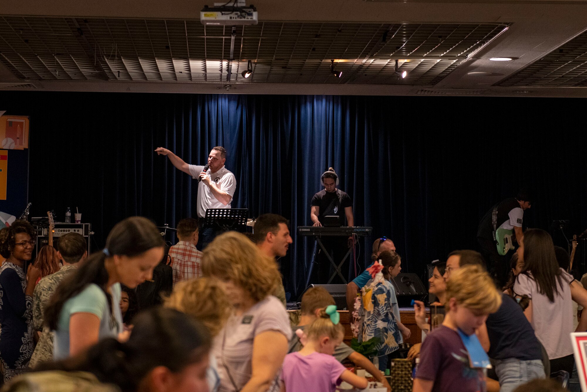 A man stands on stage and speaks before a crowd of people.