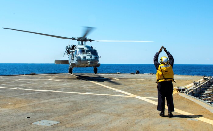 230812-N-JC445-1011 ADRIATIC SEA (August 12, 2023) Able Seaman Daries Smith, a Military Sealift Command (MSC) civilian mariner, directs a MH-60S Sea Hawk Helicopter attached to the “Ghost Riders” of Helicopter Sea Combat Squadron (HSC) 28, during flight operations from the Blue Ridge-class command and control ship USS Mount Whitney (LCC 20), the flagship of U.S. 6th Fleet. Mount Whitney is participating in Large Scale Exercise 2023 from Aug. 9-18, which is a live, virtual, and constructive, globally-integrated exercise designed to refine the synchronization of maritime operations across six maritime component commands, seven numbered fleets, and 22 time zones. (U.S. Navy photo by Mass Communication Specialist 2nd Class Mario Coto)