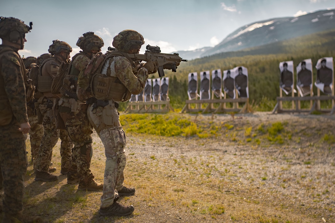 Marines stand side by side holding weapons firing at targets.