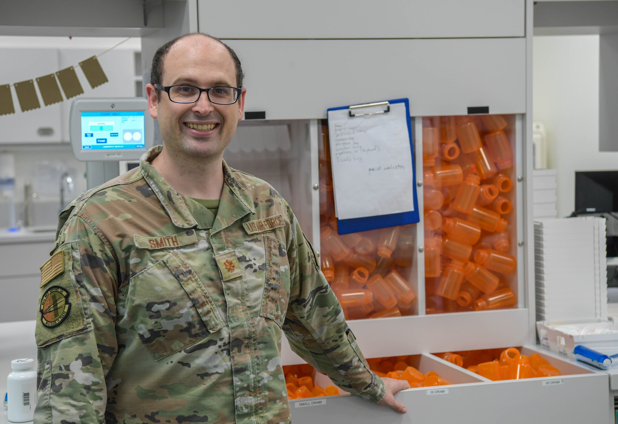 A man stands in front of an open container with prescription bottles