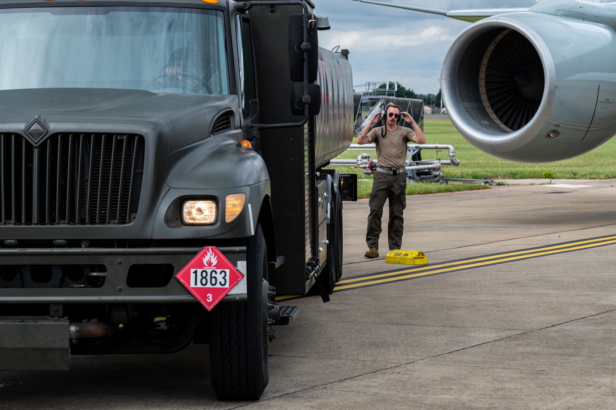 U.S. Air Force Senior Airman Michael Howard, 95th Reconnaissance Squadron crew chief, guides a fuel truck during the hot pit refueling mission of a RC-135 Rivet Joint aircraft on the flightline at Royal Air Force Mildenhall, England, Aug. 14, 2023.