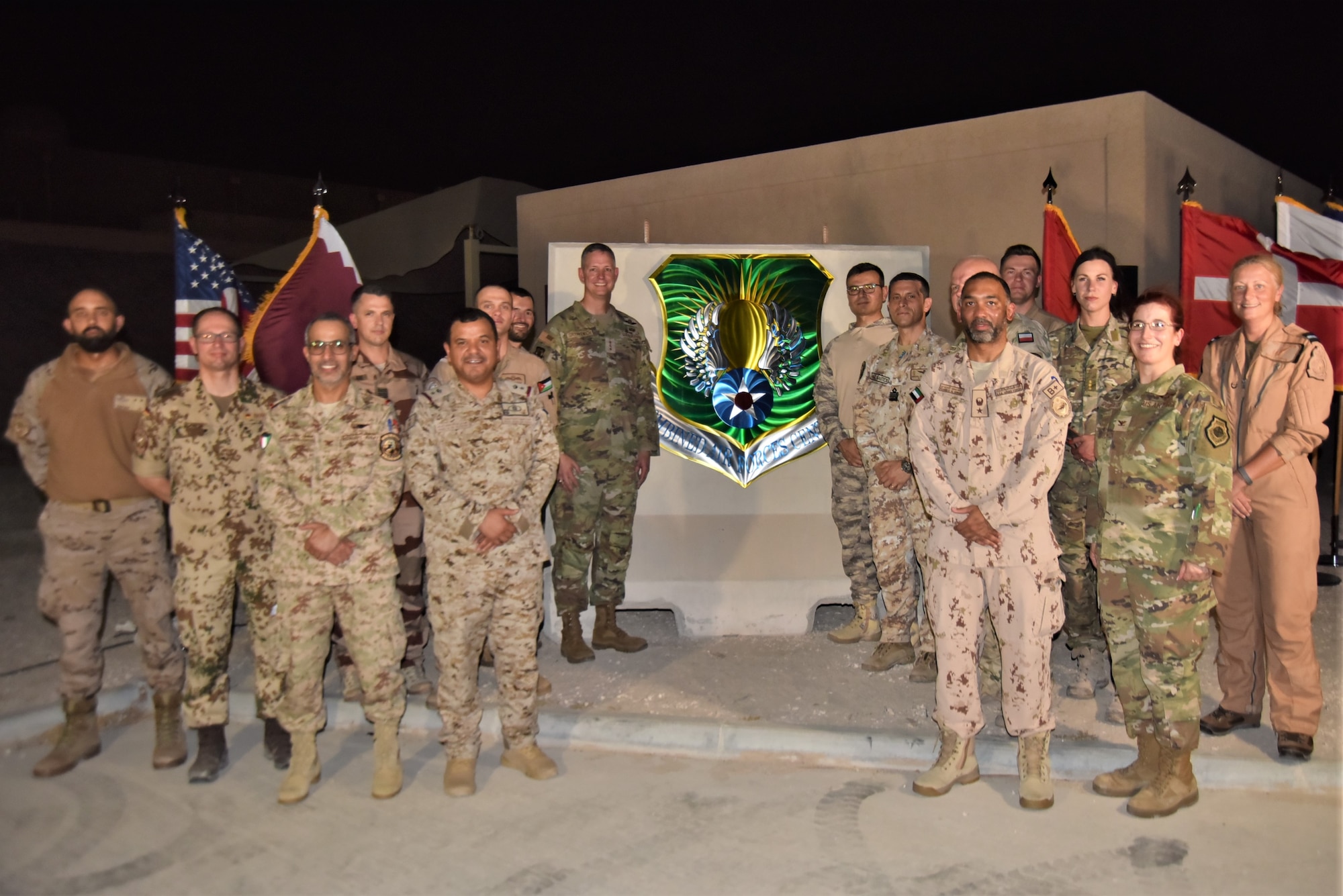 U.S. Air Force Lt. Gen. Alex Grynkewich, Ninth Air Force (AFCENT) commander and Combined Forces Air Component Commander (CFACC) for U.S. Central Command, center-left, poses for a photo with senior national representatives from coalition and partner nations during the unveiling of the new coalition and combined forces central emblem August 16, 2023, at Al Udeid Air Base, Qatar.