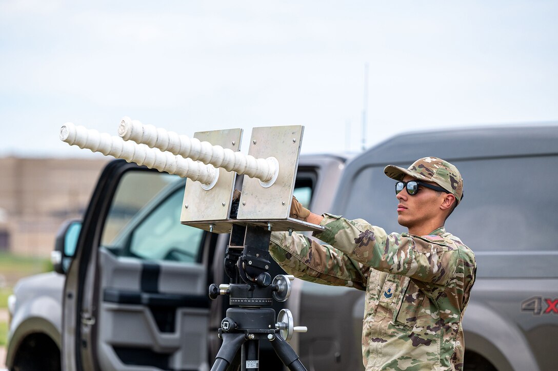 A uniformed service member operates a large piece of GPS equipment.