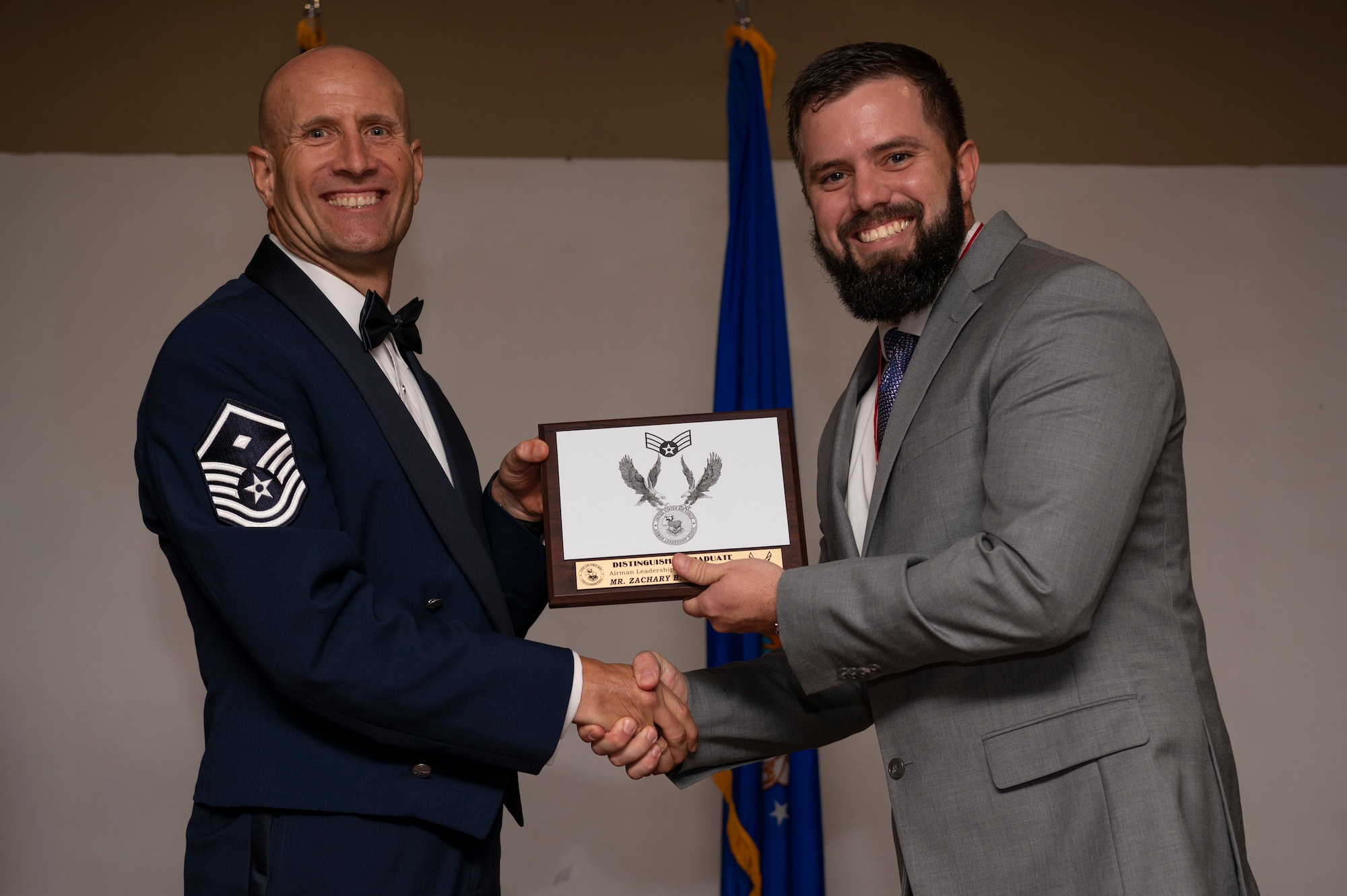 Master Sgt. Donald Sanders, 317th Operations Support Squadron first sergeant, poses for a photo with Zachary Sandefur, 7th Civil Engineering Squadron military housing assistant, at the Dyess Airman Leadership School graduation inside the Hangar Center on Dyess Air Force Base, Texas, Aug. 3, 2023. Sandefur was one of two personnel to be the first civilians to graduate from the Dyess ALS. Having civilians go through the 24-day program helps them gain perspective on enlisted professional military education and teamwork while developing a more lethal and ready force. (U.S. Air Force photo by Airman 1st Class Emma Anderson)