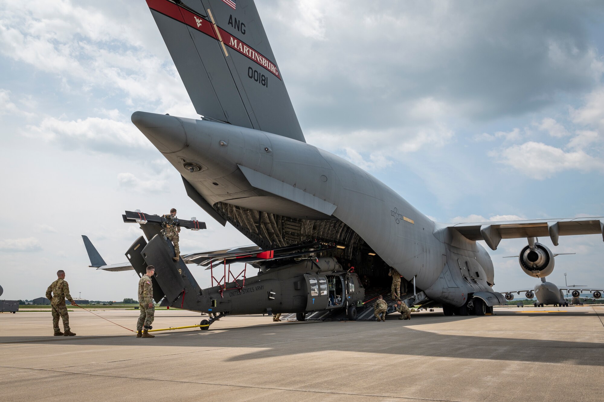 Crews from the 167th Airlift Wing and C Company, 1st Battalion, 150th Aviation Regiment conduct a joint cargo loading exercise involving a C-17 Globemaster III aircraft from the 167th and a UH-60M Black Hawk helicopter from the 150th during a readiness exercise on the 167th Airlift Wing flight line, Martinsburg, West Virginia, Aug. 11, 2023.