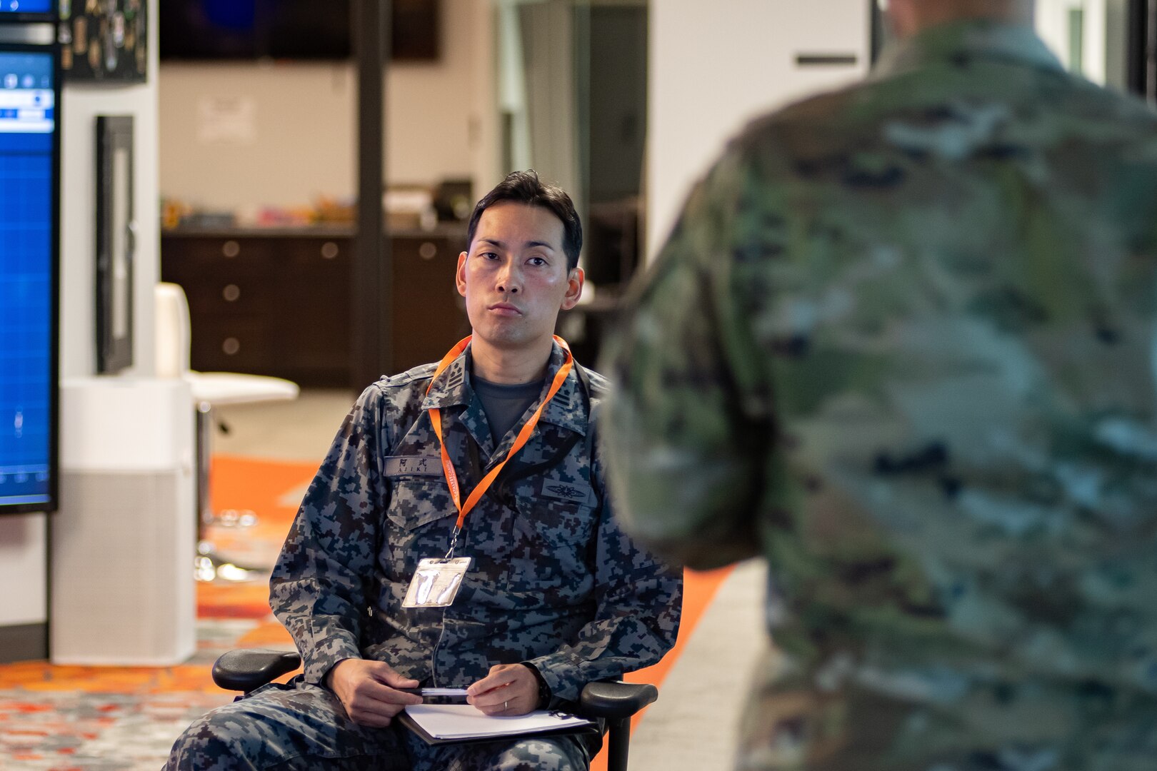 Man in Japanese uniform sits and listens to a briefing