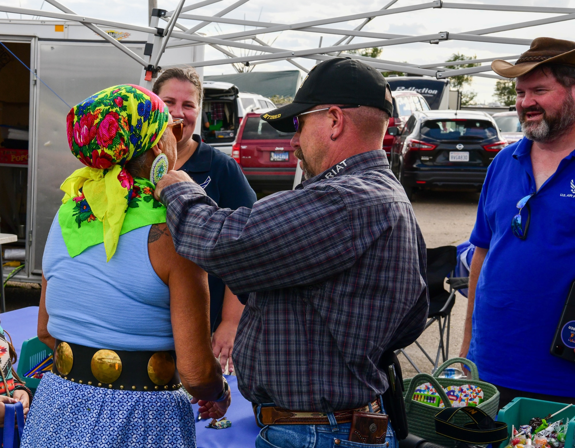 An attendee of the Mandan-Hidatsa-Arikara Nation’s Little Shell Celebration pins an American flag onto a woman’s regalia at the Air Force educational booth in New Town, N.D., Aug. 11, 2023. This outreach opportunity built relationships between the Air Force and local tribal. (U.S. Air Force photo by Abigail Kinder)
