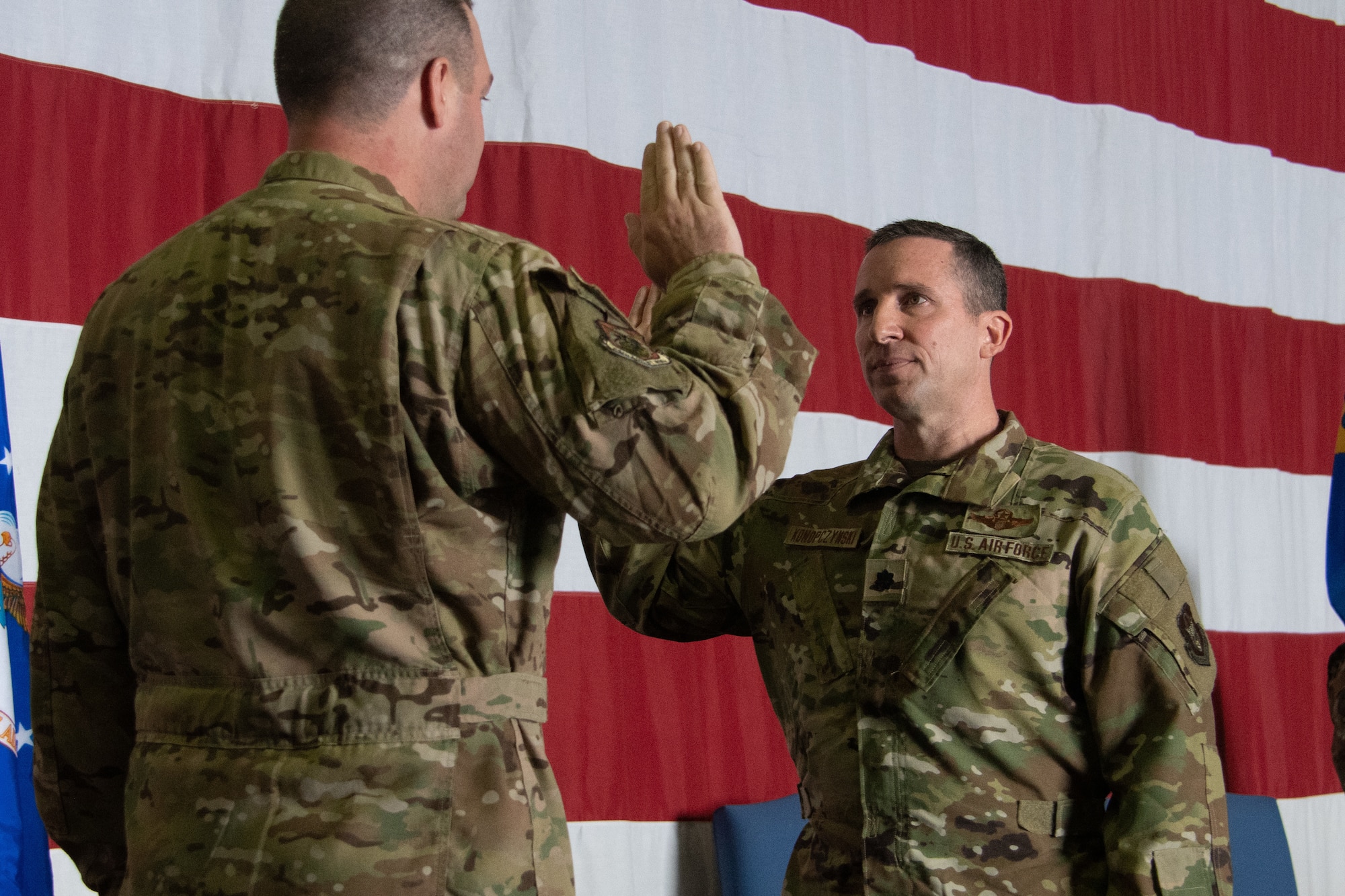 Two men stand raising their hands