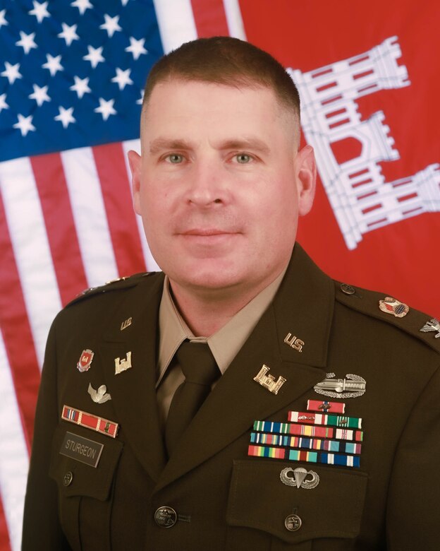 Army Col. Ronald Sturgeon in dress uniform in front of U.S. and U.S. Army Corps of Engineers flags