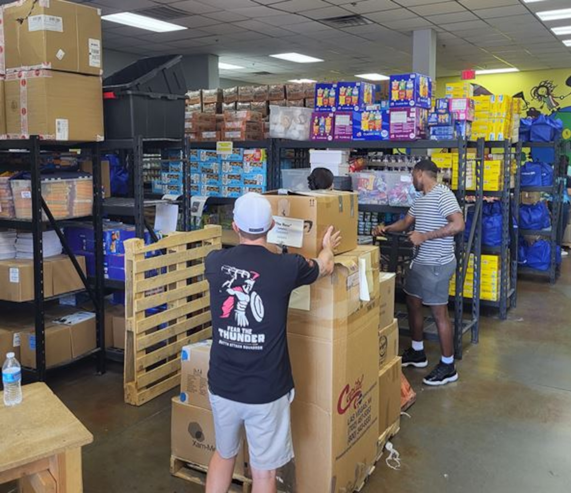 Airmen are moving donation boxes in a large room.
