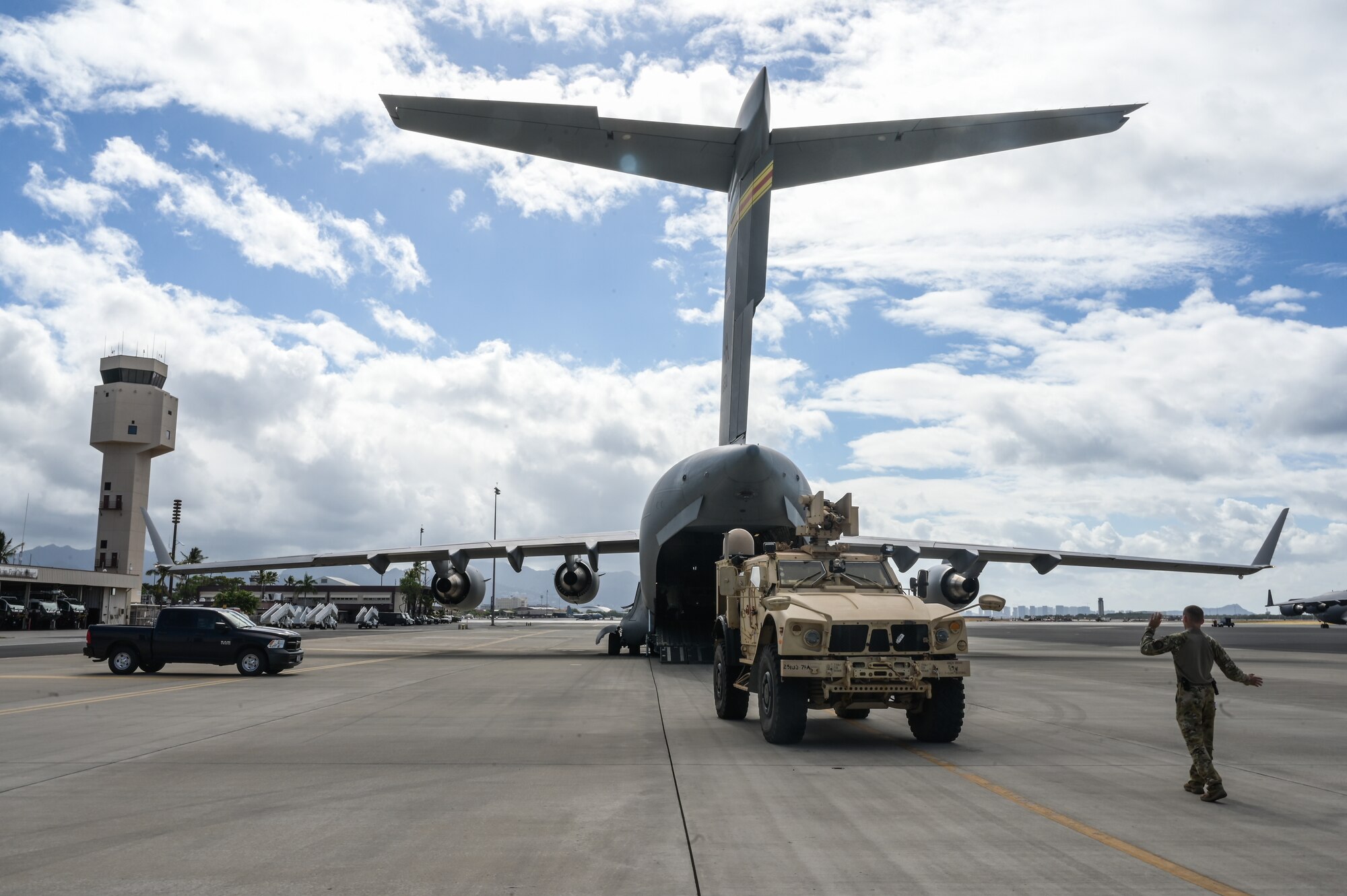 Senior Airman Jace Grayson, 535th Airlift Squadron loadmaster, directs a U.S. Army OshKosh -Mine-Resistant Ambush Protected Vehicle all-terrain vehicle into the fuselage of a C-17 Globemaster III at Joint Base Pearl Harbor-Hickam, Hawaii, August 1, 2023. Team Hickam Airmen provided transport for over 50 soldiers in support of Exercise Mungadai, a division artillery leadership training. (U.S. Air Force photo by Staff Sgt. Alan Ricker)
