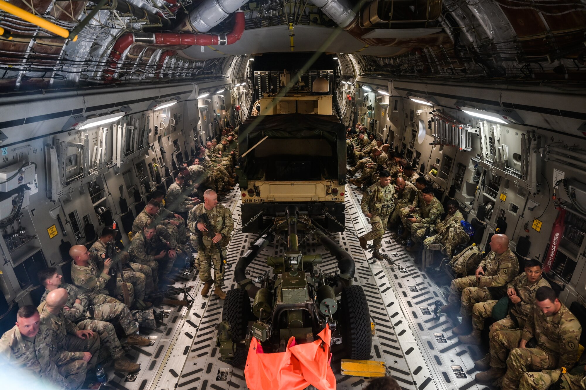 U.S. Army assigned to the 25th Infantry Division board a C-17 Globemaster III at Joint Base Pearl Harbor-Hickam, Hawaii, August 1, 2023. The C-17 was utilized to transport over 50 soldiers, a U.S. Army High Mobility Multipurpose Wheeled Vehicle, a U.S. Army M119A3 105 MM Light Towed Howitzer and a U.S. Army OshKosh -Mine-Resistant Ambush Protected Vehicle all-terrain vehicle in support of Exercise Mungadai, a division artillery leadership training. (U.S. Air Force photo by Staff Sgt. Alan Ricker)