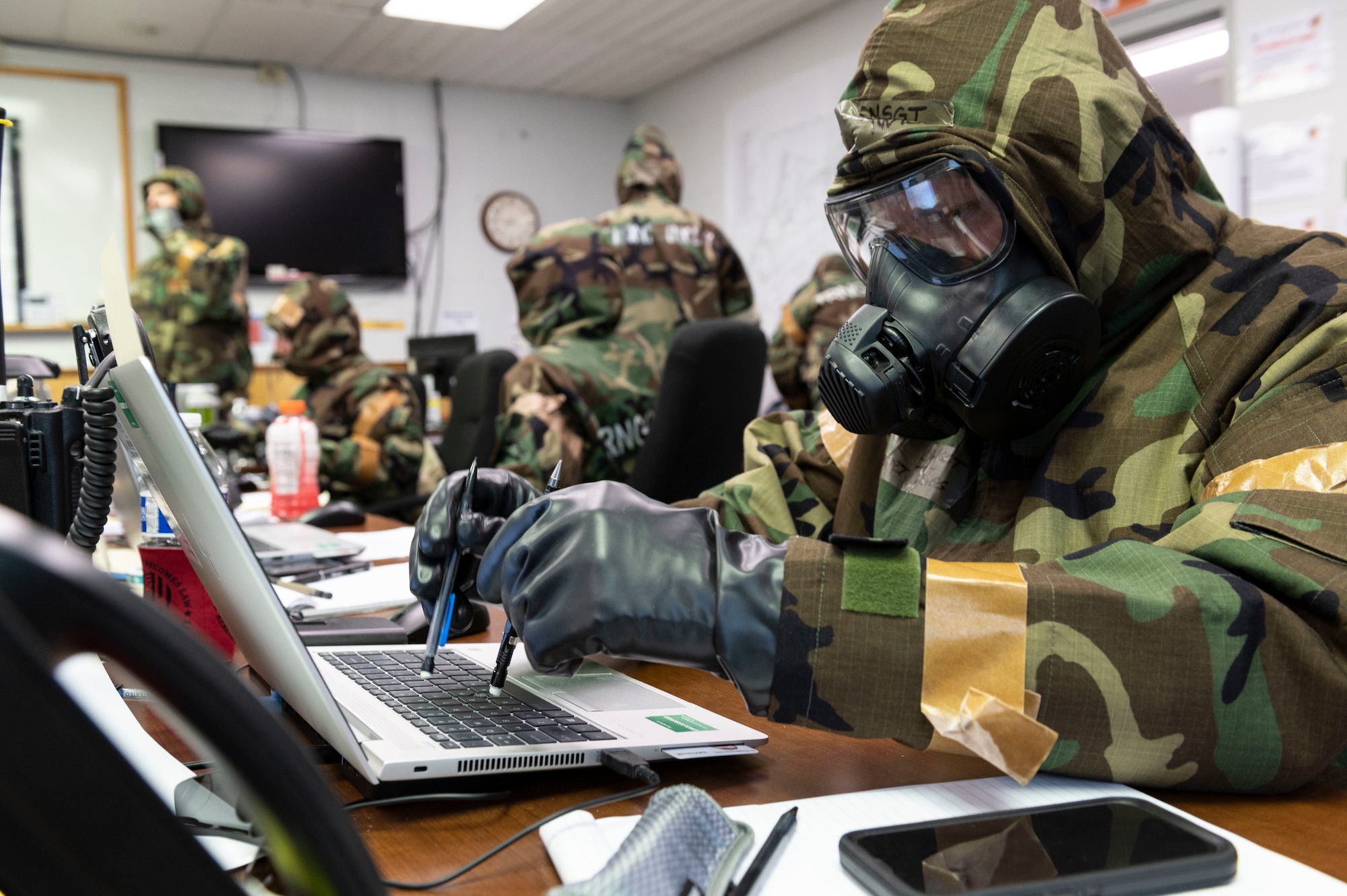 U.S. Air Force Senior Master Sgt. Dave Twigg, 167th Operations Group, maintains operations while wearing mission oriented protective gear in the emergency operation center during a readiness exercise for the 167th Airlift Wing at Shepherd Field, Martinsburg, West Virginia, Aug. 10, 2023. The exercise tested the unit’s ability to mobilize, operate and sustain its mission in degraded and contested environments through a variety of scenarios.
