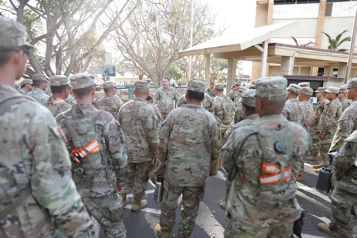 A person in uniform address a group of other people in uniform.