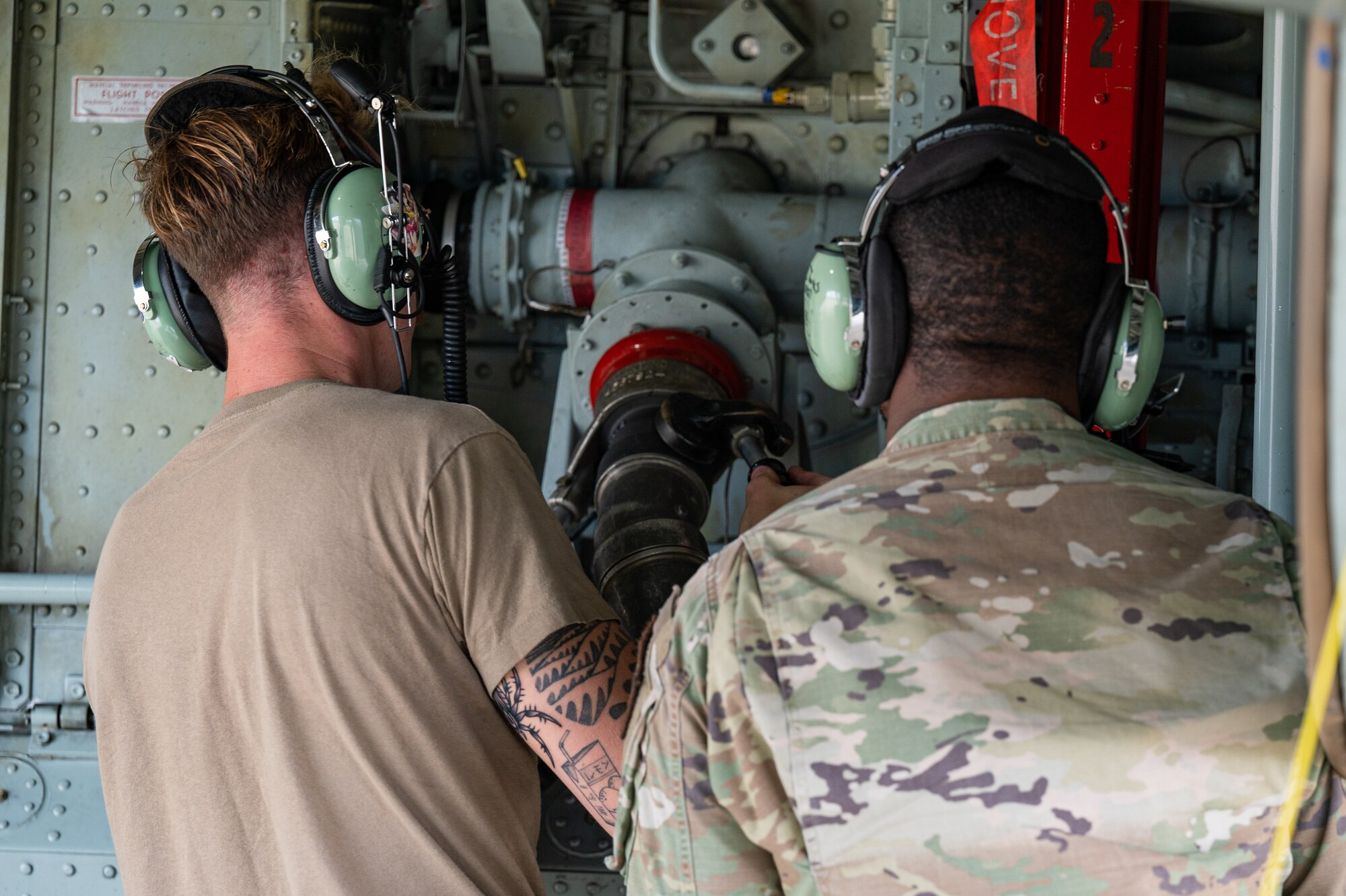 U.S. Air Force Senior Airman Michael Howard, left, 95th Reconnaissance Squadron crew chief, and Airman 1st Class Jo’von Green, right, 100th Logistics Readiness Squadron fuels distribution operator, attach a fuel hose to a RC-135 Rivet Joint aircraft on the flightline at Royal Air Force Mildenhall, England, Aug 14,2023.