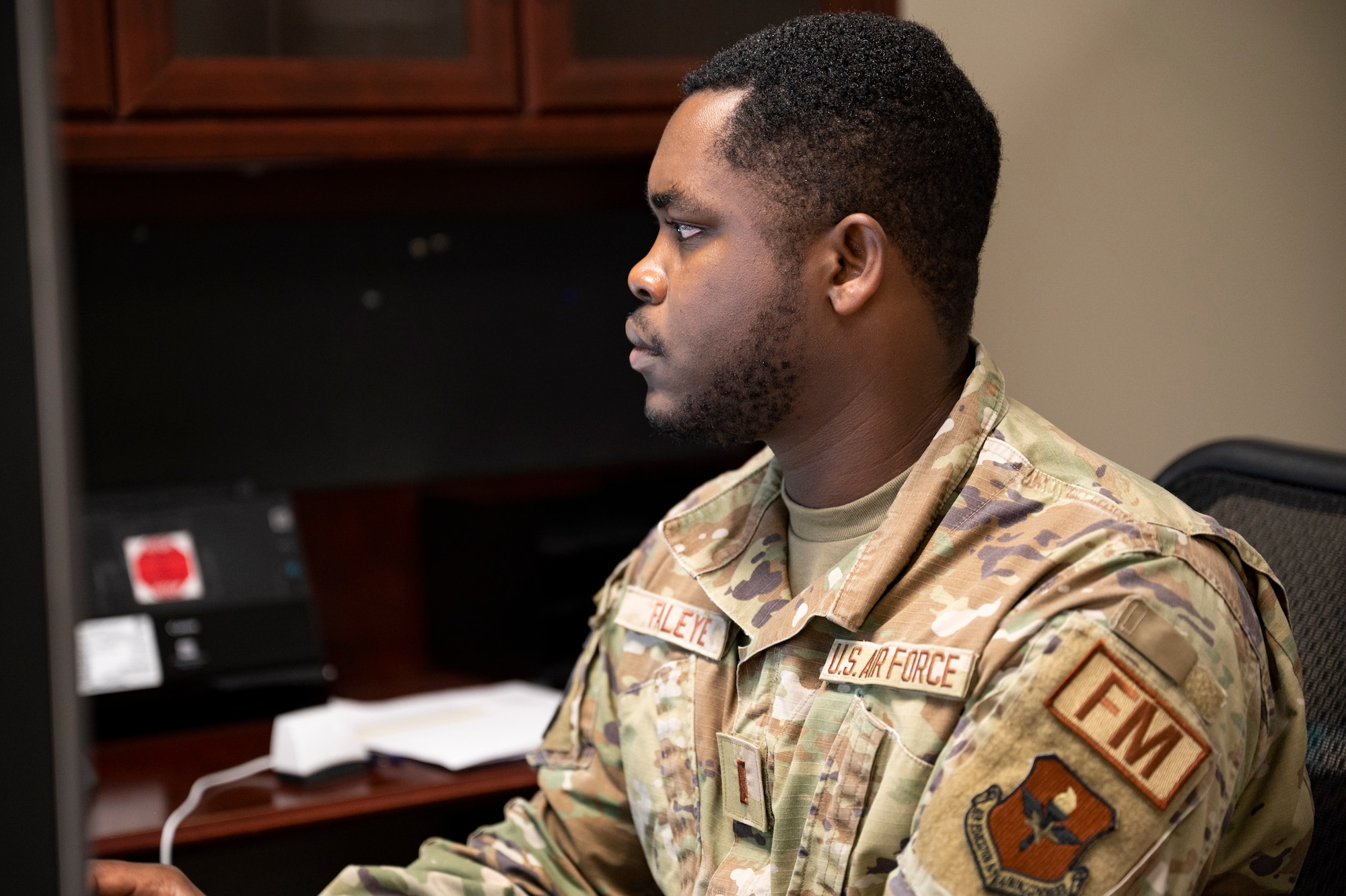 U.S. Air Force 2nd Lt. Oluwasegun Faleye, 81st Comptroller Squadron financial analysis flight deputy flight commander, is writing a decoration package on his computer at a desk.