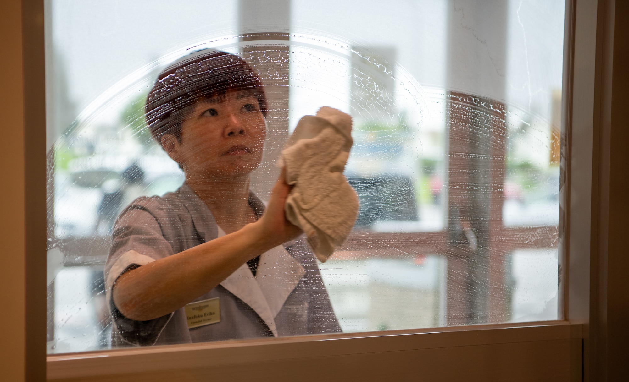 A custodial worker cleans a window.