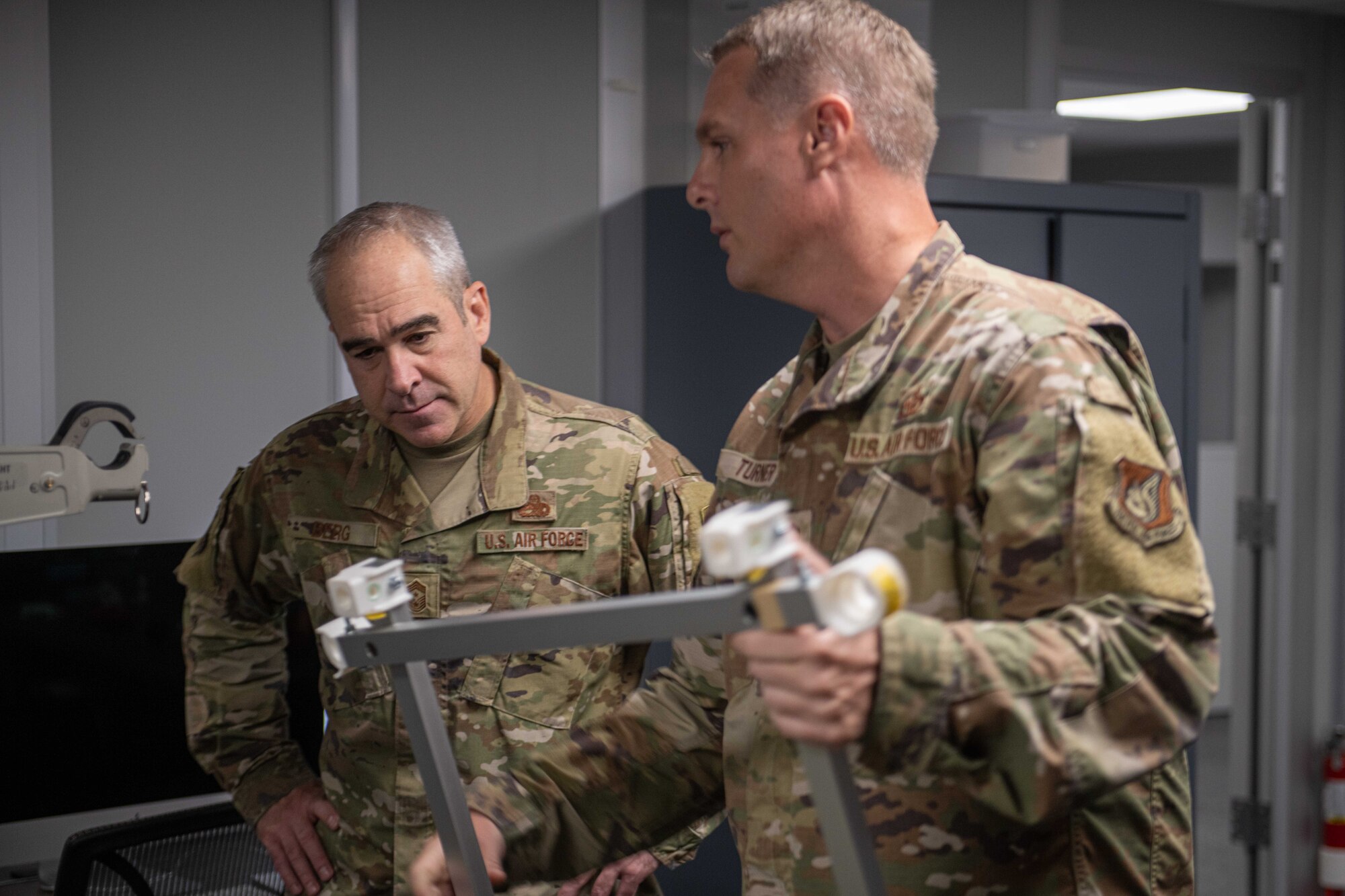 U.S. Air Force Chief Master Sgt. Kristopher Berg, 11th Air Force command chief, and U.S. Air Force Senior Master Sgt. Joshua Turner, Kadena Innovations Lab senior enlisted leader, discuss a proposed new piece of equipment.