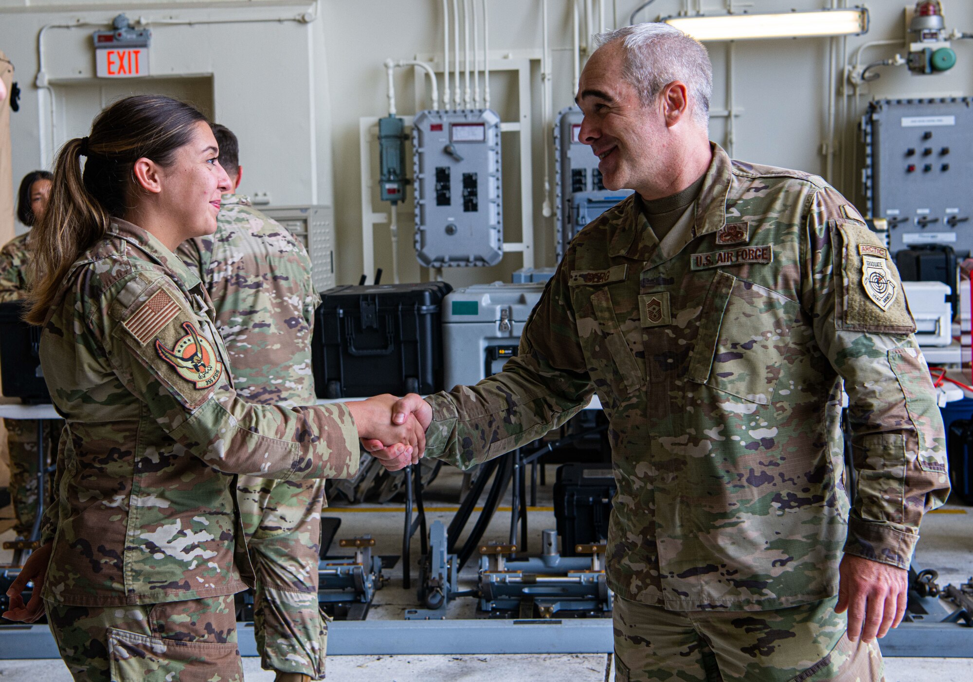 U.S. Air Force Chief Master Sgt. Kristopher Berg, 11th Air Force command chief, coins U.S. Air Force Airman 1st Class Teagan Ellis, 355th Fighter Generation Squadron weapons load crew member.