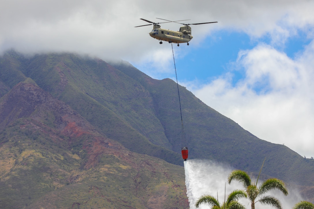 A helicopter drops water from a bambi bucket.