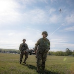 Spc. Vincent Omolon and Spc. Amber Hickman, 294th Medical Company Area Support, 67th Troop Command, Iowa National Guard, transports a patient while a medical drone gathers crucial information in-flight such as vitals, blood pressure, and more during Exercise Northern Strike 2023, on Camp Grayling, Michigan, Aug. 7, 2023.