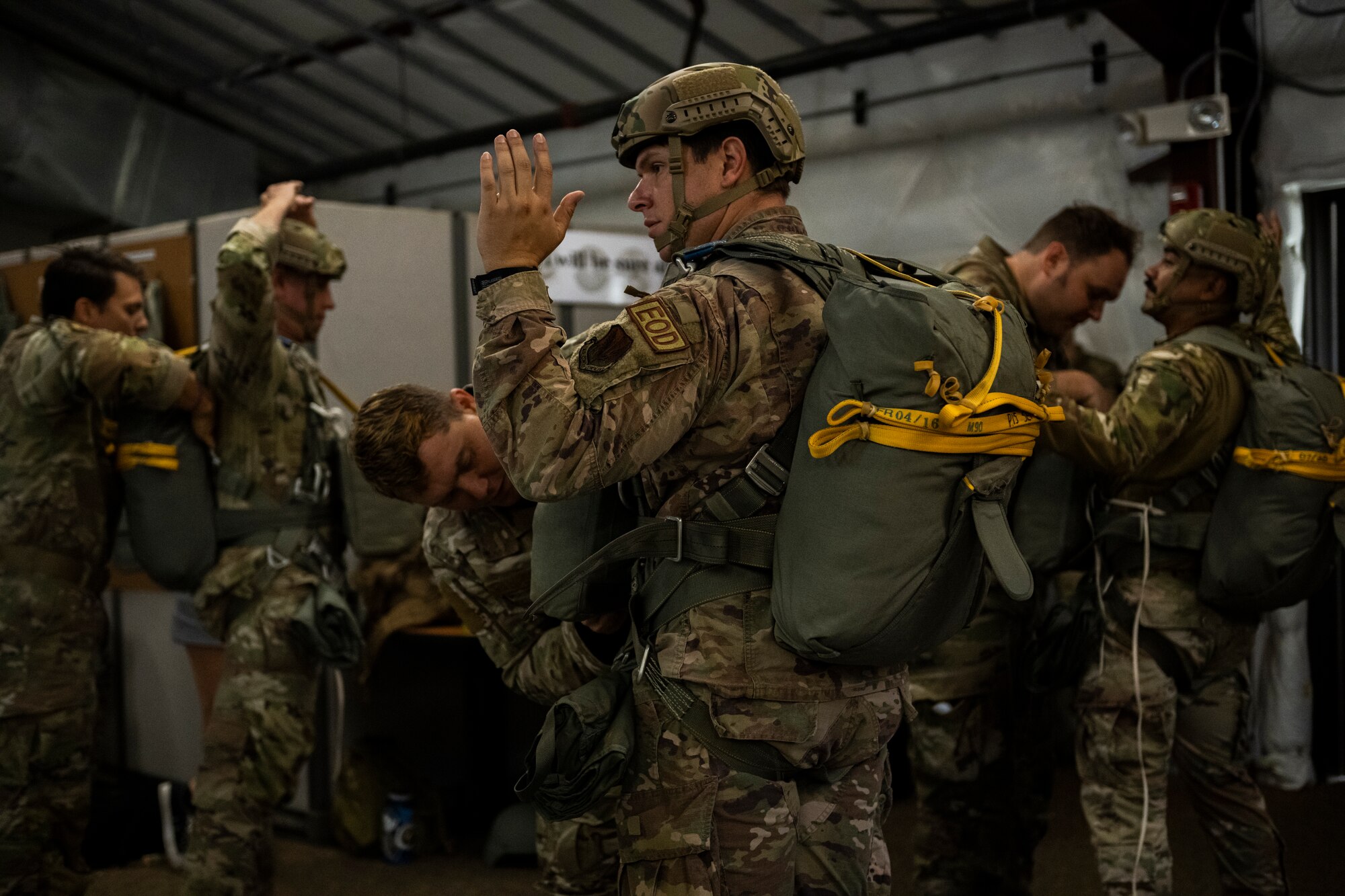 An Airman holds his arms up while his wingman checks his gear.