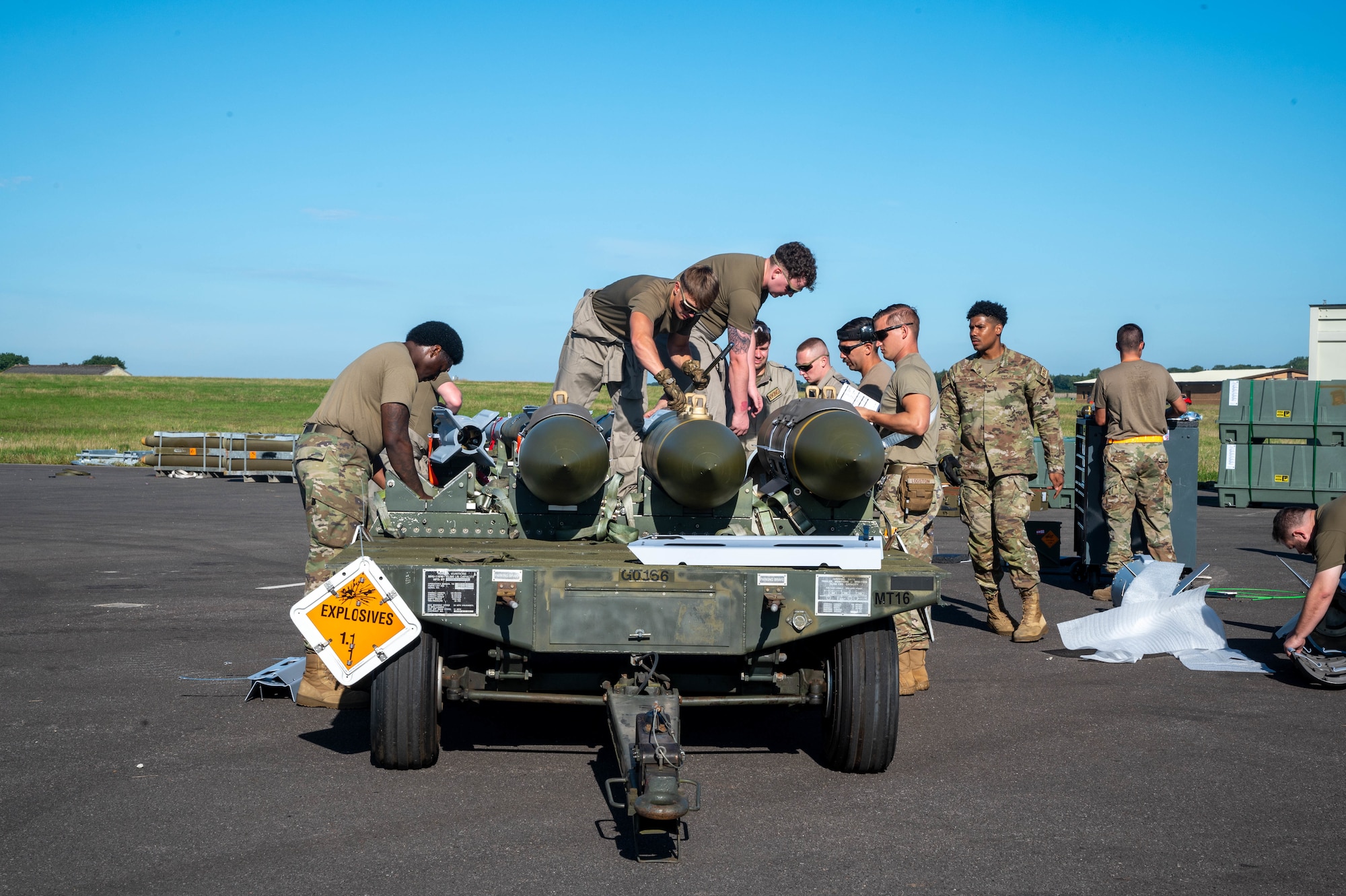 4 airmen strap munitions down to the bed of a trailer.