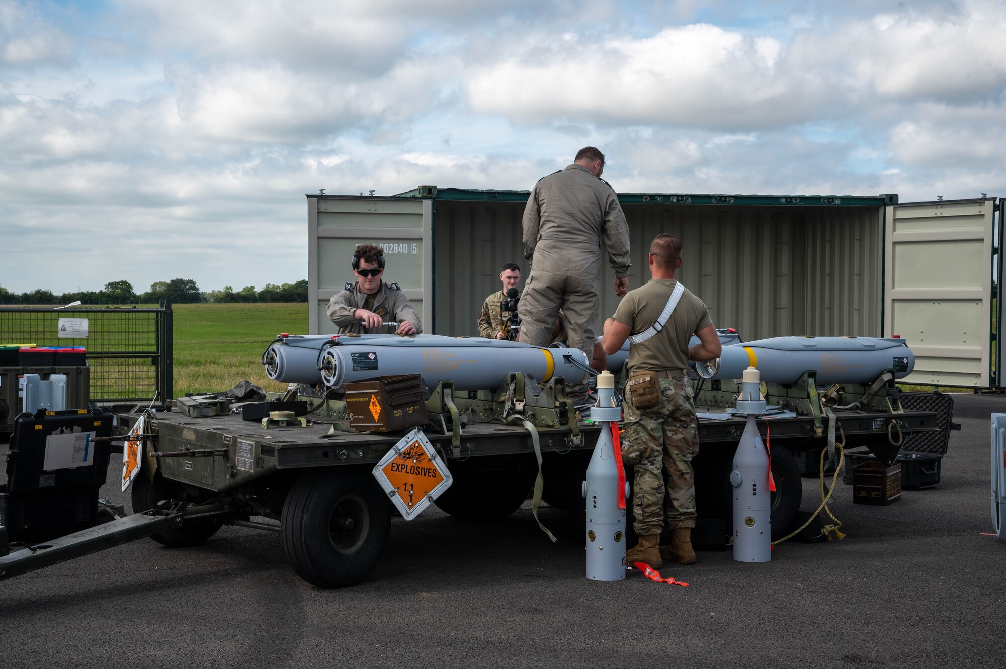 4 Airmen strapping down munitions to the bed of a trailer.