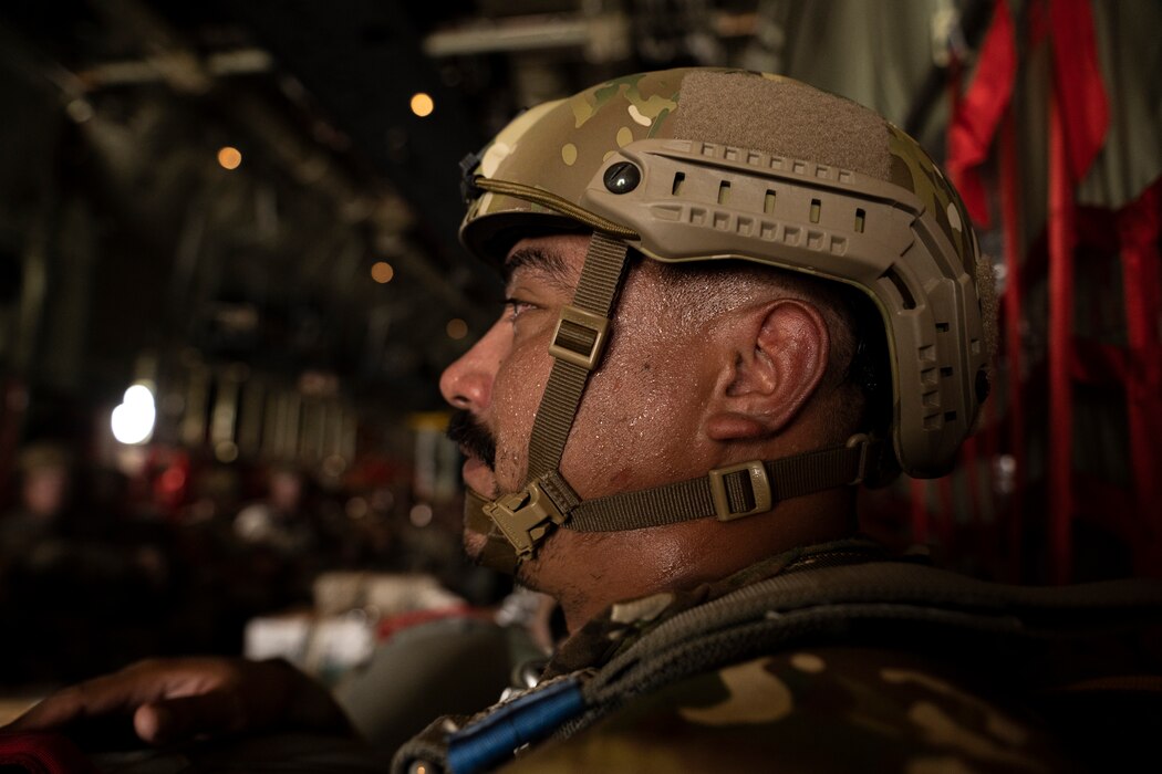 An airmen sits on a hot plane, sweating, before jumping.