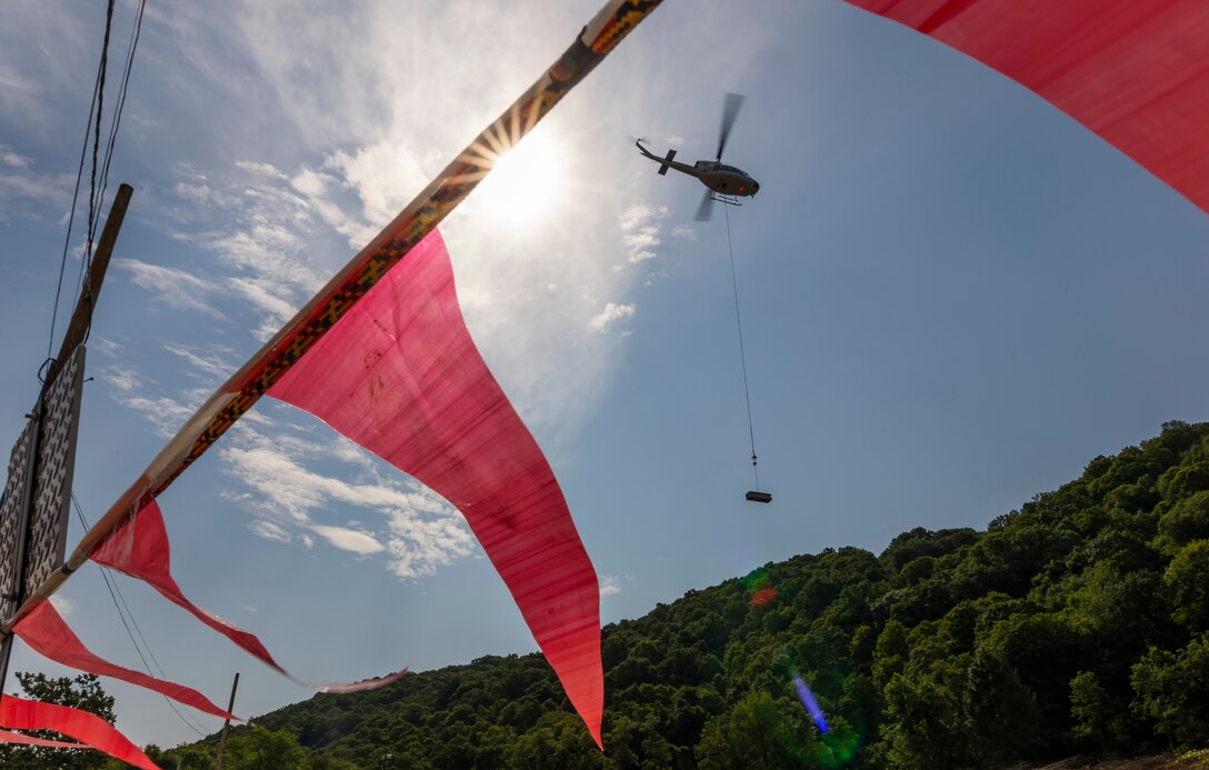 A helicopter lifting trees and concrete blocks to place them in a water basin on the Ohio River.
