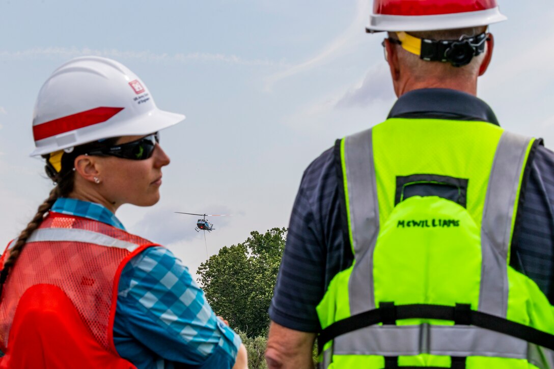 A helicopter lifting trees and concrete blocks to place them in a water basin on the Ohio River.