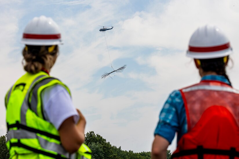 A helicopter lifting trees and concrete blocks to place them in a water basin on the Ohio River.