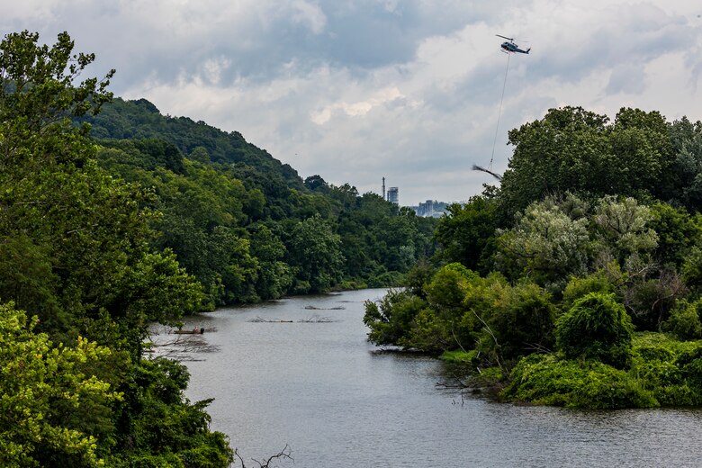 A helicopter lifting trees and concrete blocks to place them in a water basin on the Ohio River.
