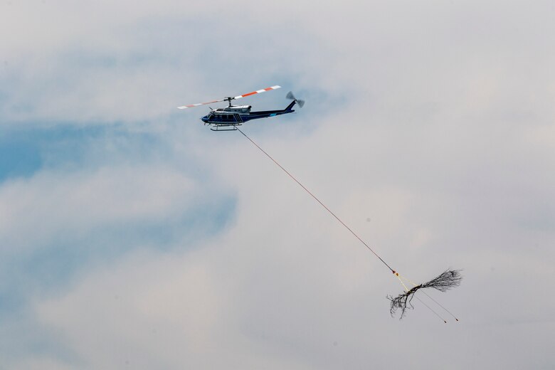 A helicopter lifting trees and concrete blocks to place them in a still water basin on the Ohio River.