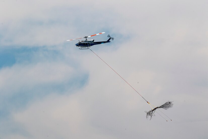 A helicopter lifting trees and concrete blocks to place them in a still water basin on the Ohio River.
