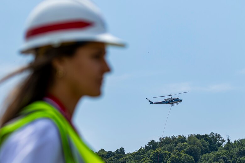 A helicopter lifting trees and concrete blocks to place them in a still water basin on the Ohio River.